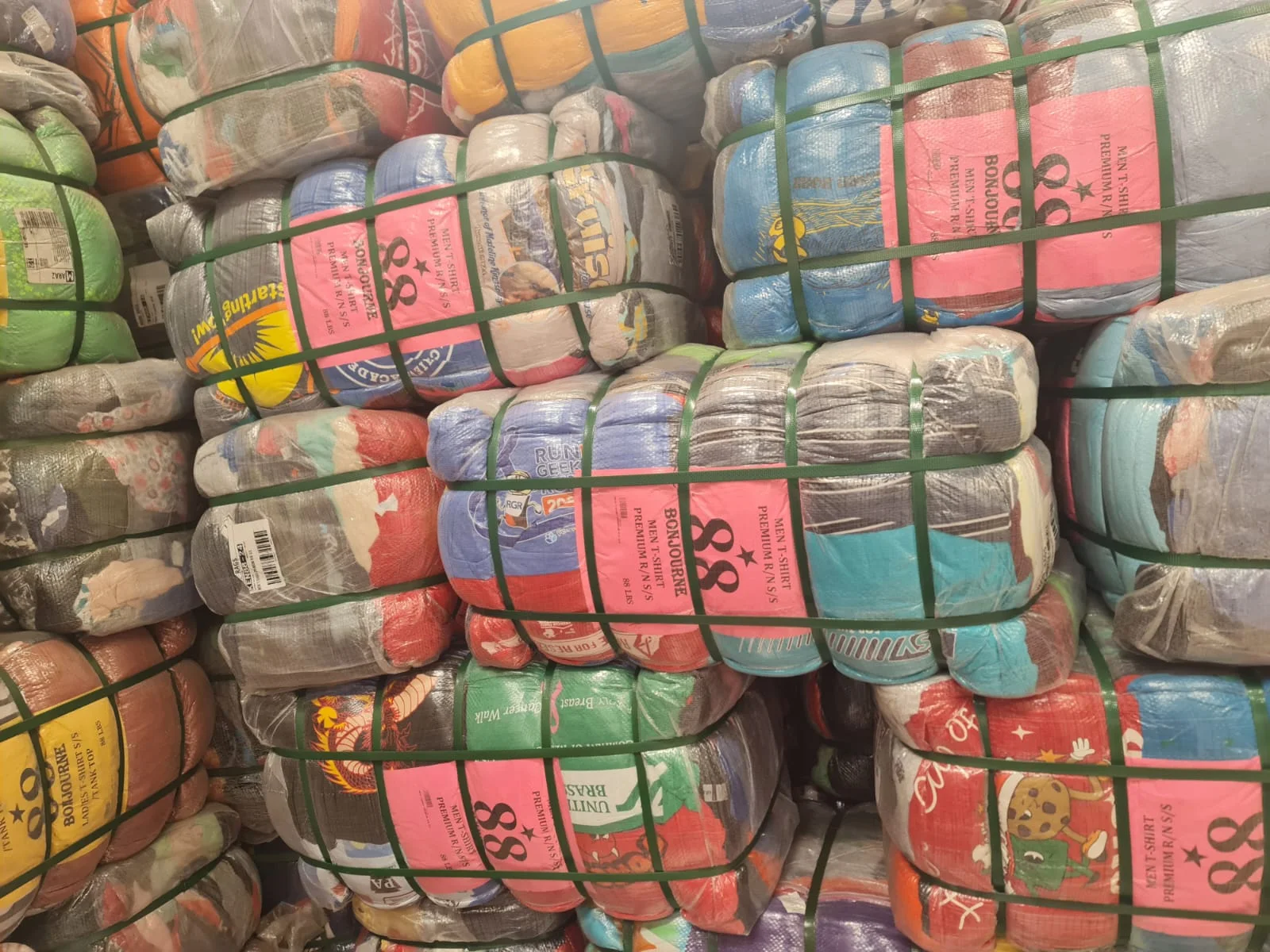 Stacks of real clothing bales secured with green straps in the Gikomba warehouse
